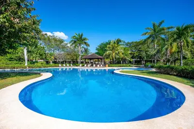 a swimming pool in a resort with palm trees at Dream House in prestigious Hacienda Pinilla in Tamarindo