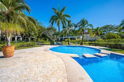 a swimming pool with palm trees and a resort at Dream House in prestigious Hacienda Pinilla in Tamarindo