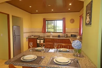 a kitchen with a table with plates and wine glasses at Beautiful 2 Bedroom Villa with Private Nature Reserve - Friendship House in Bijagua