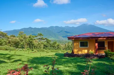 a small house in a field with mountains in the background at Beautiful 2 Bedroom Villa with Private Nature Reserve - Friendship House in Bijagua
