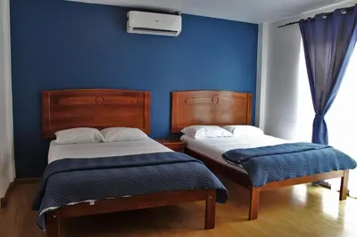 two beds in a room with a blue wall at Park View Hotel & Restaurant in Alajuela City