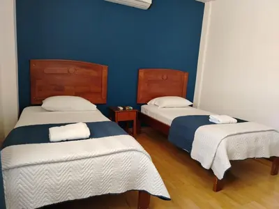 two beds in a room with a blue wall at Park View Hotel & Restaurant in Alajuela City