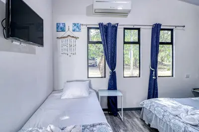 a room with two beds and a tv and two windows at Casa Conchas in Carrillo