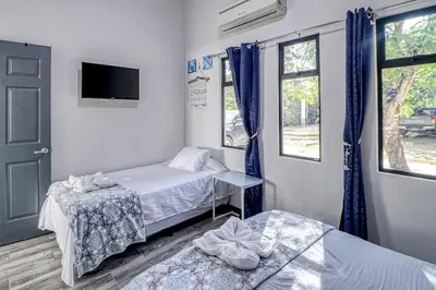 a room with two beds and a tv and a window at Casa Conchas in Carrillo