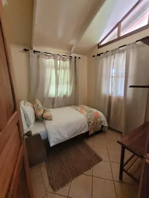 a small bedroom with a bed and a window at Cabina Rancho la Merced in Uvita