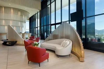 a lobby with a white chair and red chairs at Hilton San Jose La Sabana in San José