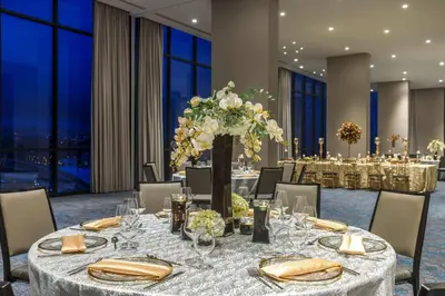 a dining room with a long table with a large vase of flowers at Hilton San Jose La Sabana in San José