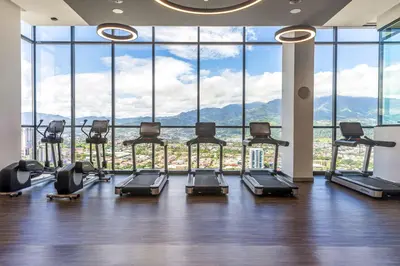 a gym with a bunch of exercise equipment in front of a large window at Hilton San Jose La Sabana in San José