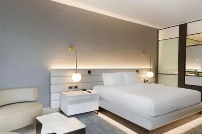 a bedroom with a large white bed and a chair at Hilton San Jose La Sabana in San José