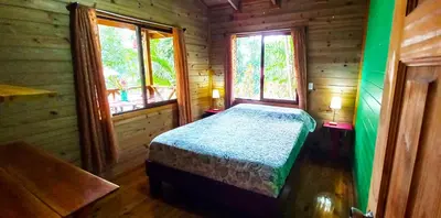 a bedroom with a bed in a wooden cabin at Cabinas Costa Tropicana in Uvita