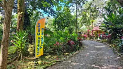 a sign on the side of a road in a garden at Cabinas Costa Tropicana in Uvita