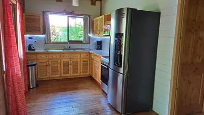 a kitchen with a stainless steel refrigerator and wooden cabinets at Cabinas Costa Tropicana in Uvita