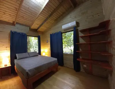 a bedroom with a bed in a log cabin at Cabinas Costa Tropicana in Uvita