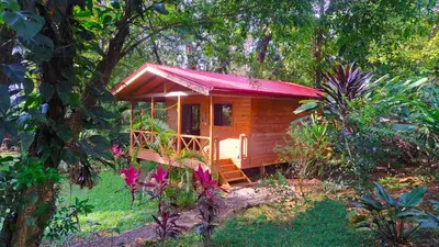a small wooden cabin with a red roof at Cabinas Costa Tropicana in Uvita