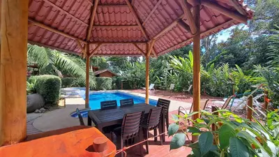a patio with a table and chairs and a pool at Cabinas Costa Tropicana in Uvita