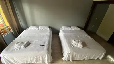 two beds with dogs laying on them in a room at Hotel Puerto San Luis in Tilarán