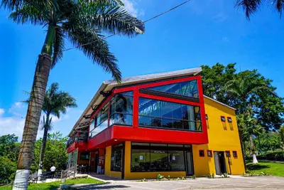 a yellow and red building with a palm tree at Hotel Puerto San Luis in Tilarán