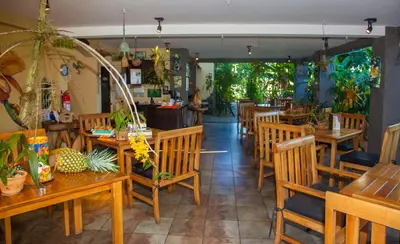 a restaurant with wooden tables and chairs in a room at Pura Vida Hotel in Alajuela City