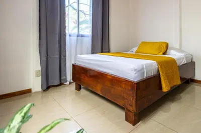 a bed with a wooden frame in a room at Casa kattleya in Tortuguero