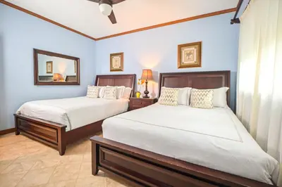 a bedroom with two beds and a mirror at Veranda 1H 3 bdr Garden View in Los Suenos in Herradura