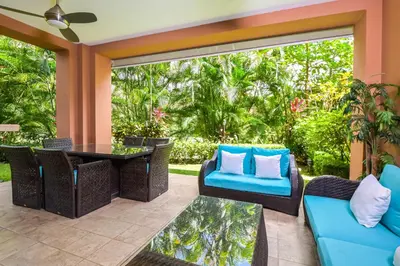 a patio with blue chairs and a table and a window at Veranda 1H 3 bdr Garden View in Los Suenos in Herradura