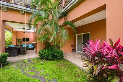a house with a palm tree in a yard at Veranda 1H 3 bdr Garden View in Los Suenos in Herradura