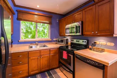 a kitchen with wooden cabinets and a stove and a sink at Veranda 1H 3 bdr Garden View in Los Suenos in Herradura