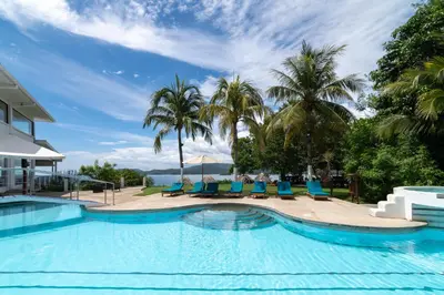 a swimming pool with blue chairs and palm trees at Dunama Ocean View Hotel in Playa Flamingo