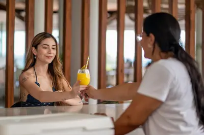 two women sitting at a table with a drink at Dunama Ocean View Hotel in Playa Flamingo
