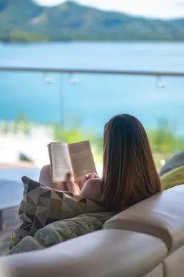 a woman laying on a couch reading a book at Dunama Ocean View Hotel in Playa Flamingo