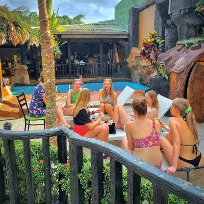 a group of women in bathing suits sitting by a pool at Poshtel Arenal in Fortuna
