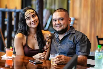 a man and a woman sitting at a table at Poshtel Arenal in Fortuna