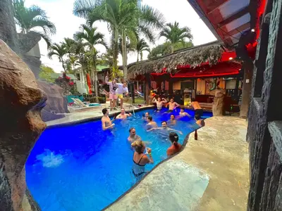 a group of people in a swimming pool at a resort at Poshtel Arenal in Fortuna