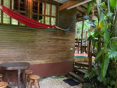 a wooden house with a bench and a table at FLOR DE PARAISO BUNGALOWS in Montezuma