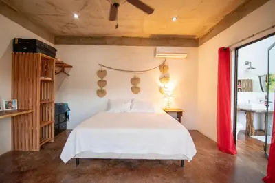 a bedroom with a white bed with a red curtain at Marbella Retreats Casa Roja in Santa Cruz