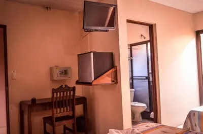 a room with a desk and a television on the wall at Hotel La Choza Inn in Fortuna