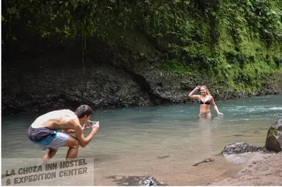 a woman taking a picture of a woman in the water at Hotel La Choza Inn in Fortuna