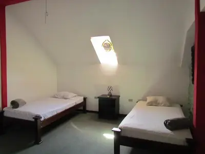 two beds in a room with a light on the ceiling at Hostel Shakti in San José