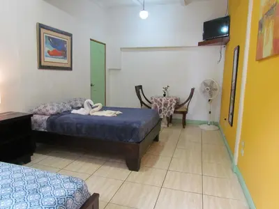 a bedroom with two beds and a table and a chair at Hostel Shakti in San José