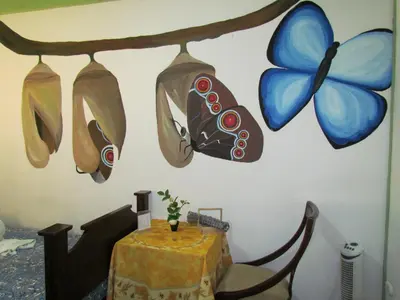 a room with a table and a butterfly painted on the wall at Hostel Shakti in San José