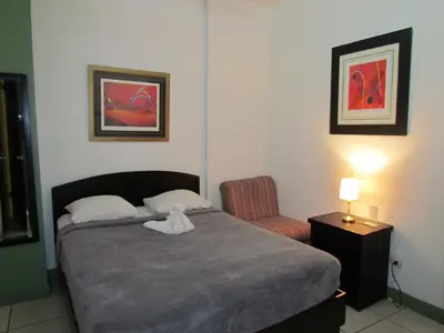 a small bedroom with a bed and a chair at Hostel Shakti in San José