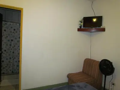 a living room with a chair and a tv on the wall at Hostel Shakti in San José