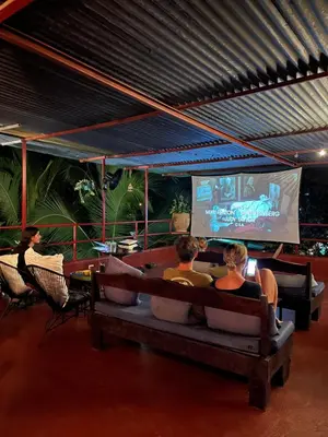 a group of people sitting on a couch watching a screen at Villas Jacquelina in Quepos