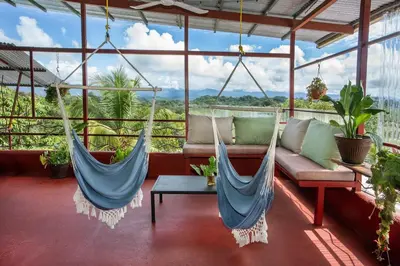 two hammocks in a room with a couch and a table at Villas Jacquelina in Quepos