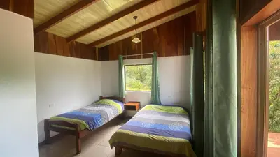two beds in a room with a window at Cabinas Capulin & Farm in Monteverde Costa Rica