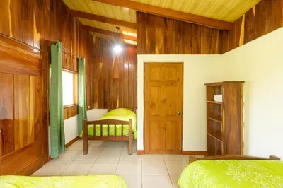 a room with two beds and a wooden wall at Cabinas Capulin & Farm in Monteverde Costa Rica