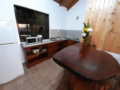 a kitchen with a wooden table and a refrigerator at Cabinas Capulin & Farm in Monteverde Costa Rica