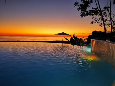 a swimming pool with a sunset in the background at Vista Ballena in Uvita