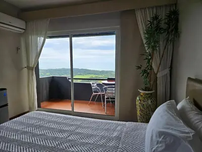 a bedroom with a bed and a balcony with a table at Vista Ballena in Uvita