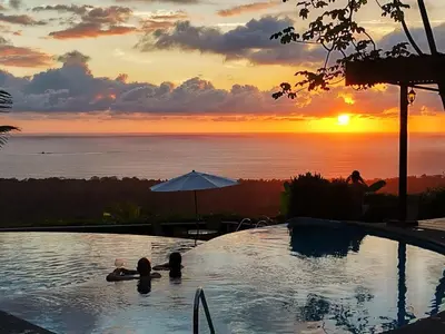 a swimming pool with a sunset in the background at Vista Ballena in Uvita